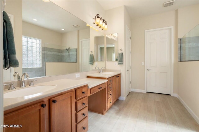 bathroom featuring hardwood / wood-style flooring, tiled shower, and vanity