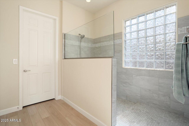 bathroom with hardwood / wood-style floors and a tile shower