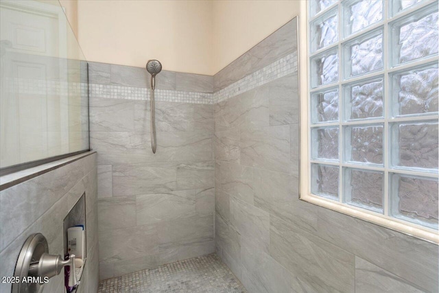 bathroom featuring a tile shower and a healthy amount of sunlight