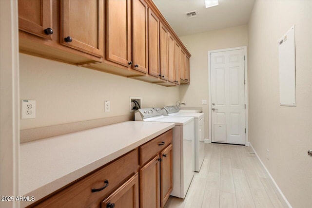 washroom featuring cabinets, light hardwood / wood-style floors, and washer and dryer