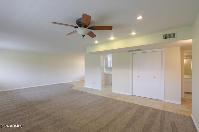 unfurnished bedroom featuring ceiling fan, a closet, light carpet, and connected bathroom