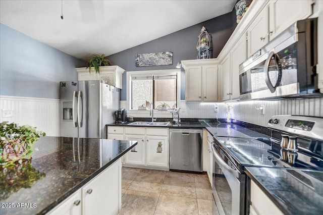 kitchen featuring vaulted ceiling, stainless steel appliances, light tile patterned floors, white cabinetry, and sink