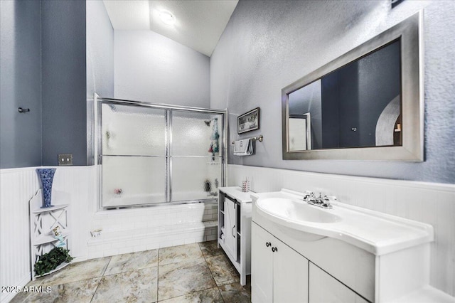 bathroom with a textured ceiling, shower / bath combination with glass door, lofted ceiling, and vanity