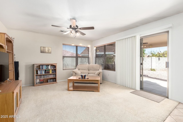 living room featuring light carpet, visible vents, baseboards, and a ceiling fan