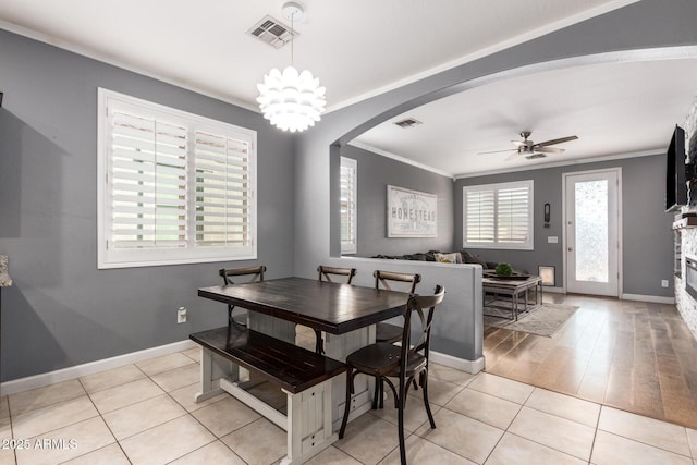 dining room featuring arched walkways, visible vents, crown molding, and ceiling fan with notable chandelier