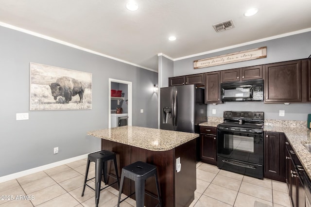 kitchen featuring visible vents, ornamental molding, dark brown cabinets, washer and dryer, and black appliances