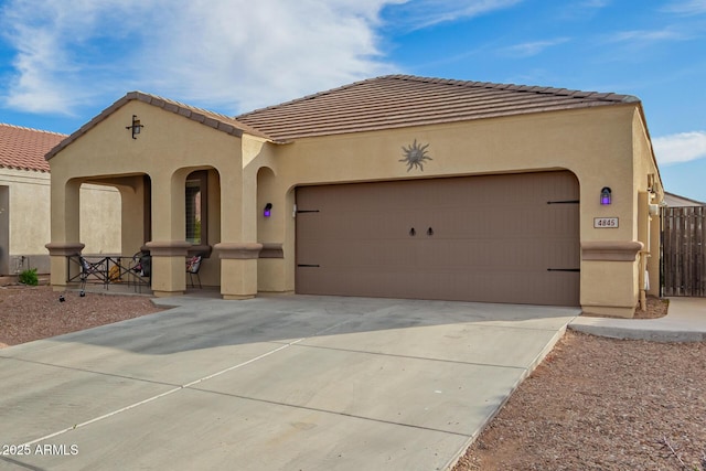 mediterranean / spanish house with driveway, an attached garage, a tile roof, and stucco siding