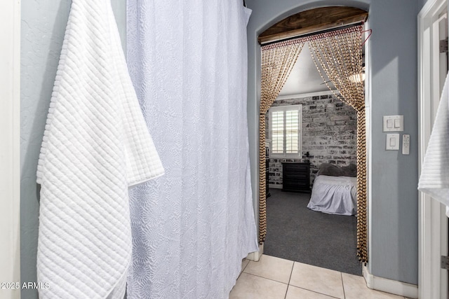 ensuite bathroom featuring tile patterned flooring, connected bathroom, and brick wall