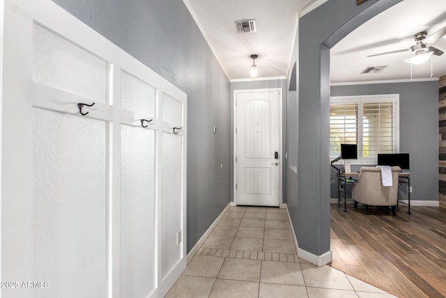 entryway with light tile patterned floors, baseboards, visible vents, and ornamental molding