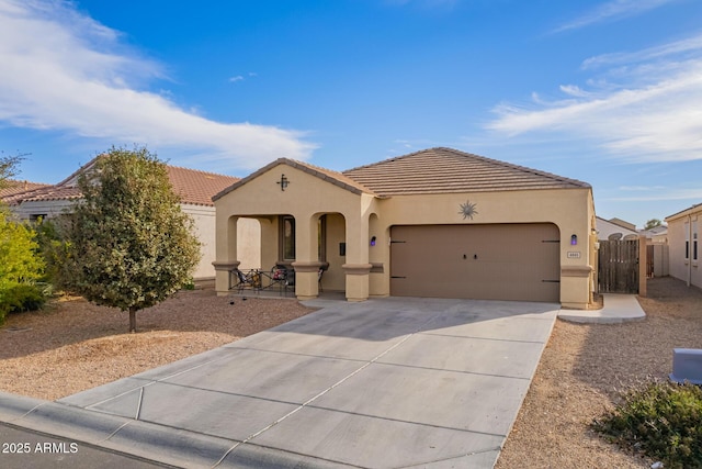 mediterranean / spanish house with a garage, concrete driveway, a tile roof, and stucco siding