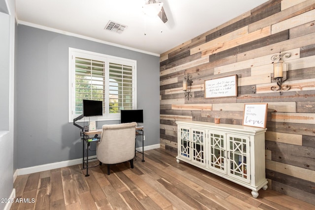 office space with visible vents, wooden walls, baseboards, and wood finished floors