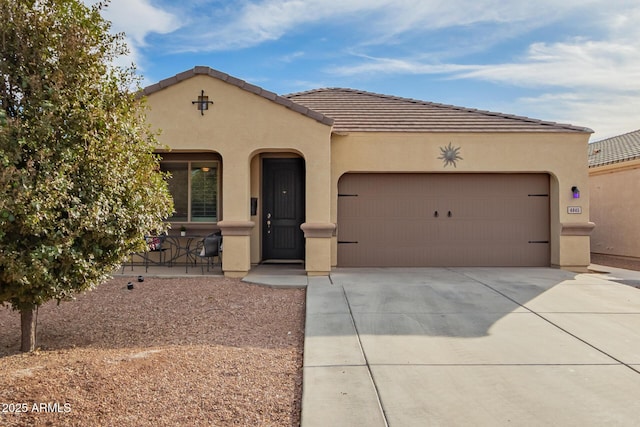 mediterranean / spanish house with a garage, concrete driveway, a tile roof, and stucco siding