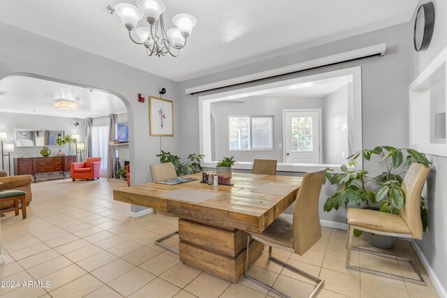 dining room with light tile patterned floors, baseboards, arched walkways, and a chandelier