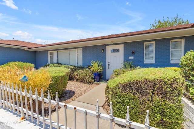 ranch-style home featuring a fenced front yard and brick siding