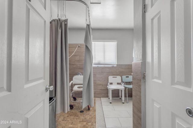 bathroom featuring tile patterned flooring, a wainscoted wall, and tile walls