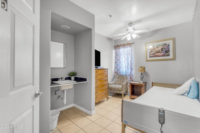 bedroom featuring a sink, baseboards, a ceiling fan, and light tile patterned flooring