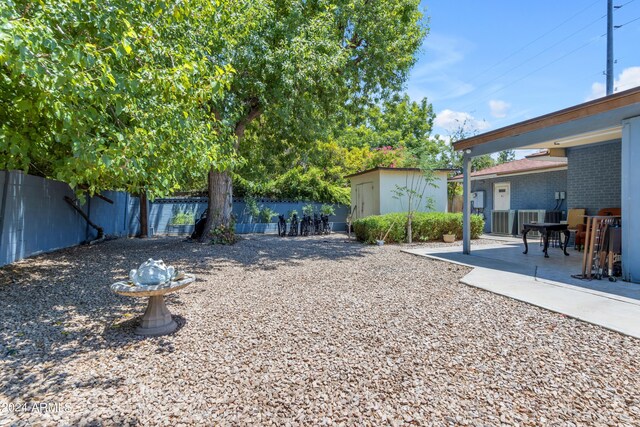 view of yard featuring a patio area, a fenced backyard, and an outdoor structure