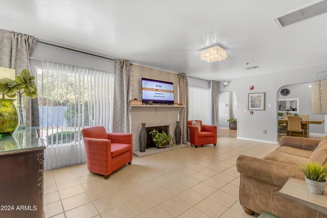 living room featuring baseboards, visible vents, arched walkways, a fireplace, and light tile patterned flooring