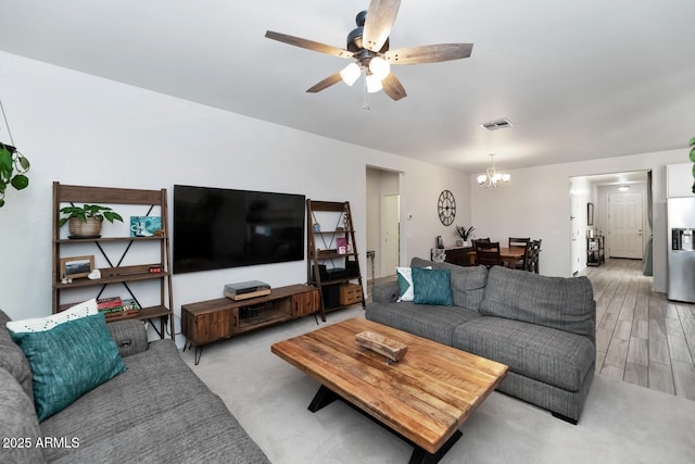 living area featuring ceiling fan with notable chandelier, light wood-style floors, and visible vents