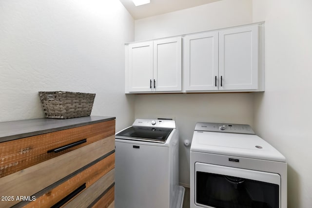 clothes washing area featuring washing machine and dryer and cabinet space