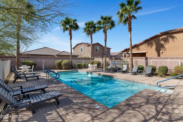 community pool with a patio area and fence