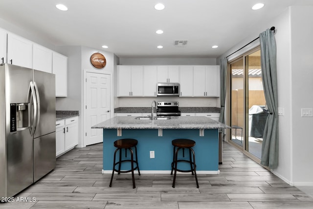 kitchen with a breakfast bar area, visible vents, wood finish floors, a sink, and stainless steel appliances