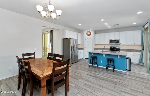 dining area with visible vents, light wood finished floors, baseboards, recessed lighting, and a notable chandelier