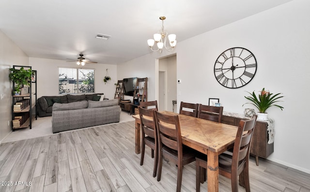 dining space featuring visible vents, light wood-style flooring, and ceiling fan with notable chandelier