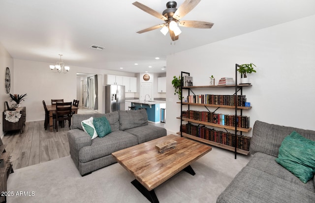 living room with recessed lighting, visible vents, ceiling fan with notable chandelier, and light wood-style flooring