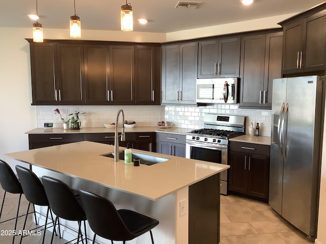 kitchen with appliances with stainless steel finishes, dark brown cabinets, a sink, and tasteful backsplash
