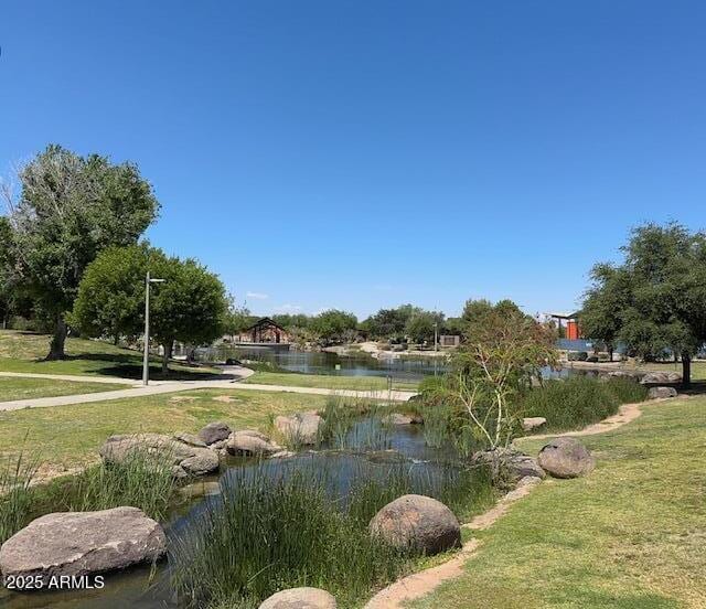 view of property's community with a lawn and a water view