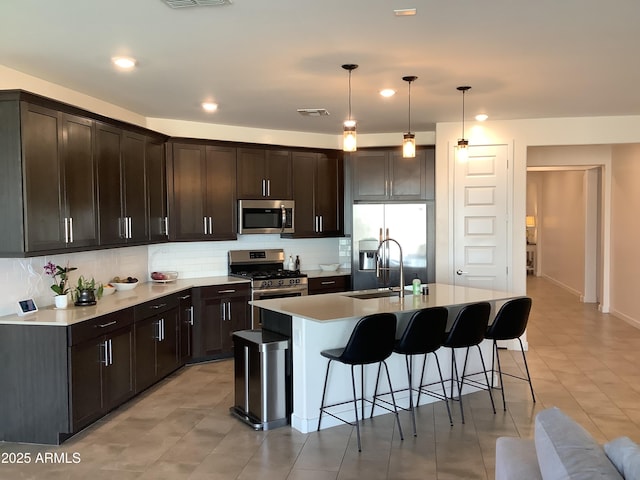 kitchen featuring tasteful backsplash, a sink, a breakfast bar area, stainless steel appliances, and visible vents