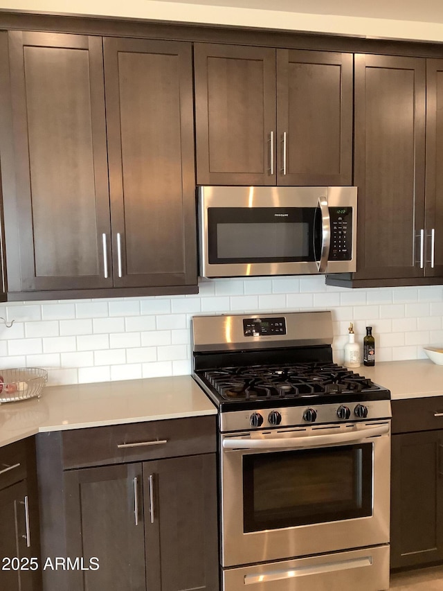 kitchen with light countertops, backsplash, appliances with stainless steel finishes, and dark brown cabinetry