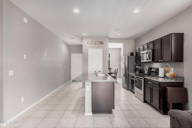 kitchen with dark brown cabinetry, light tile patterned floors, visible vents, appliances with stainless steel finishes, and a sink