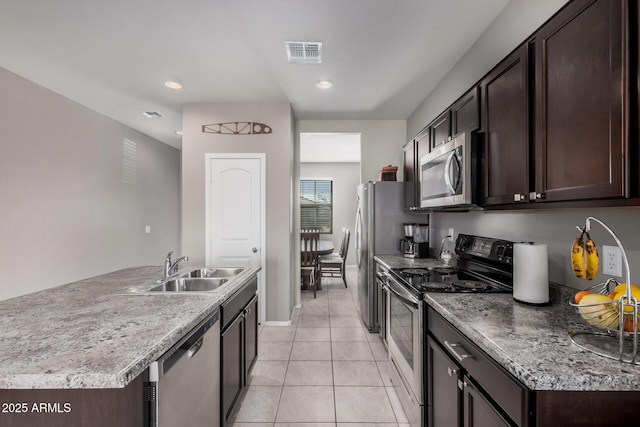 kitchen featuring visible vents, appliances with stainless steel finishes, light tile patterned flooring, a sink, and dark brown cabinetry