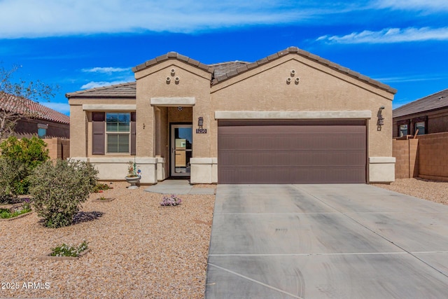 mediterranean / spanish-style home featuring driveway, a tiled roof, fence, and stucco siding