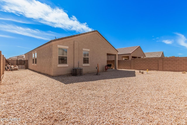 back of house featuring central AC unit, a tile roof, a fenced backyard, and stucco siding