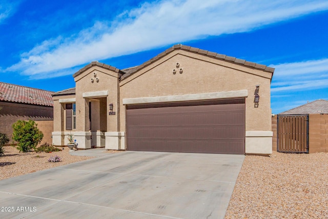 mediterranean / spanish-style home featuring a tile roof, stucco siding, concrete driveway, an attached garage, and fence