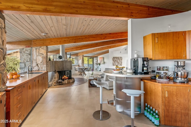 kitchen with sink, wood ceiling, lofted ceiling with beams, and a multi sided fireplace