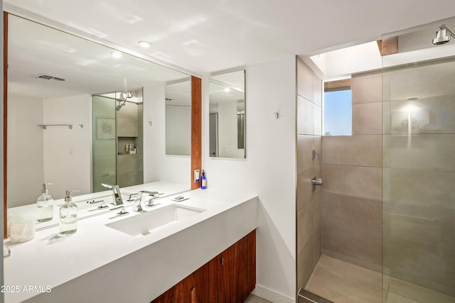 bathroom with vanity and a tile shower