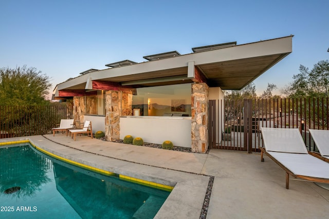 back house at dusk with a fenced in pool and a patio