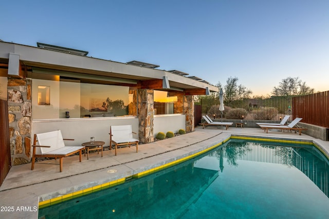 pool at dusk featuring a patio