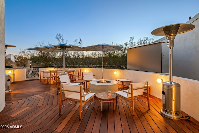 deck at dusk with cooling unit and an outdoor fire pit