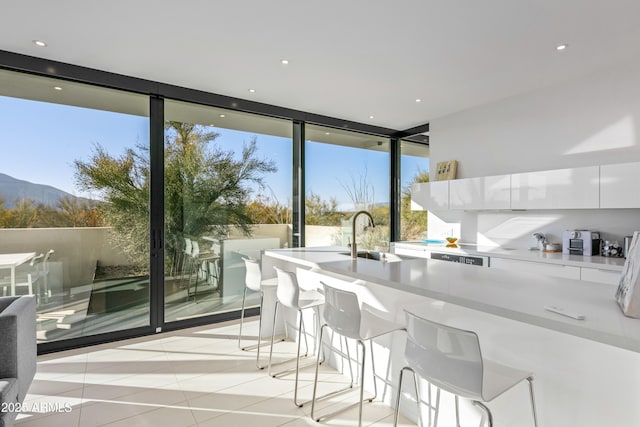 interior space featuring white cabinets, a kitchen bar, expansive windows, light tile patterned floors, and a mountain view