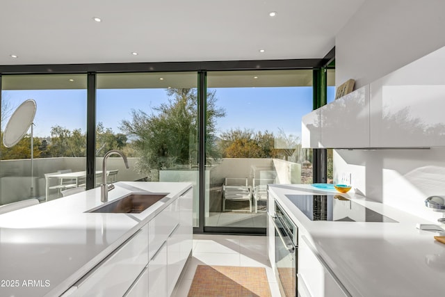 doorway to outside with a wall of windows, sink, and light tile patterned floors