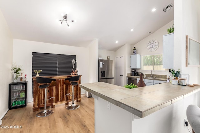 19230 N 5th St, Phoenix, AZ 85024 - kitchen featuring appliances with stainless steel finishes, light wood-style flooring, a peninsula, lofted ceiling, and recessed lighting