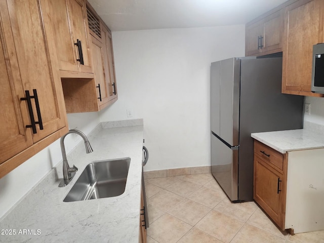 kitchen featuring light tile patterned flooring, appliances with stainless steel finishes, light stone countertops, and sink