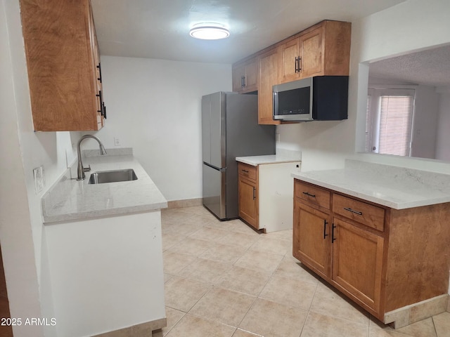 kitchen featuring appliances with stainless steel finishes, light stone countertops, sink, and light tile patterned floors