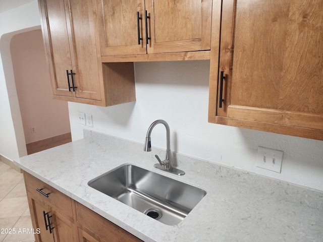 kitchen featuring sink, light tile patterned floors, and light stone counters