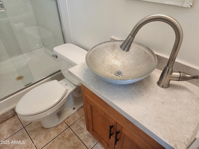 bathroom with a shower with door, vanity, tile patterned floors, and toilet